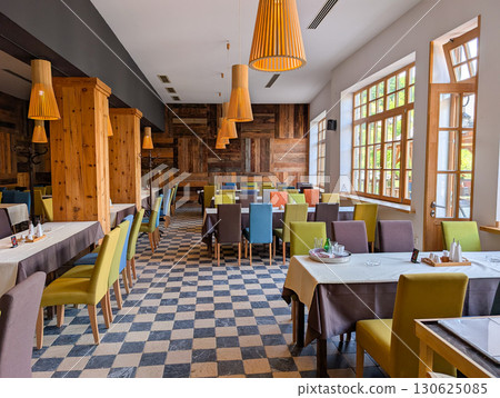 Dining hall with colorful seating and rustic decor. Social atmosphere, hospitality, rural tourism and wooden architecture. 130625085