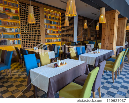 Restaurant interior with colorful chairs and book wall. Modern rustic dining, leisure, hospitality and cultural heritage. Restaurant interior with colorful chairs and book wall. Modern rustic dining, leisure, hospitality and cultural heritage. 130625087