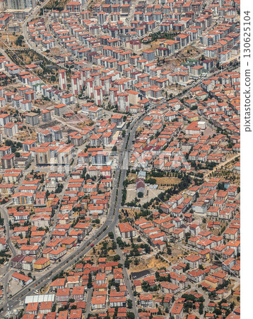 An aerial view of a dense cityscape Turkey with red-roofed apartment blocks and streets. Urban growth, architecture, and residential development forming a modern neighborhood pattern. 130625104