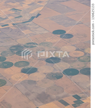 Aerial view of circular farmland patterns across rural landscape in Turkey. Agriculture, irrigation, and environmental management creating geometric scenery of cultivated earth from above. 130625133