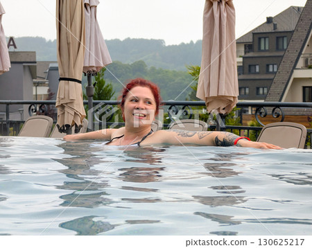 Smiling woman enjoying relaxation in pool. Holiday, leisure, and calm travel experience. 130625217