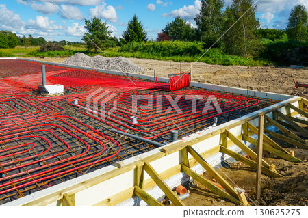 Concrete foundation with red underfloor heating pipes and thermal insulation at construction site Concrete foundation with red underfloor heating pipes and thermal insulation at construction site 130625275