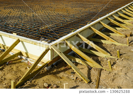 Close-up of rebar foundation with wooden formwork braces for concrete slab construction site 130625288