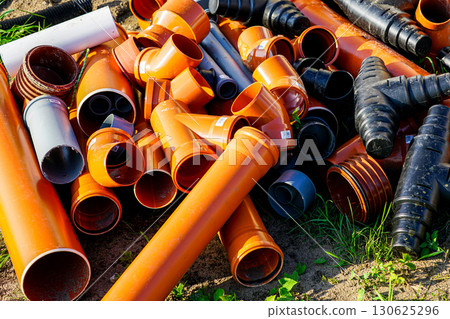 Pile of plastic construction pipes and fittings for drainage and plumbing on outdoor building site 130625296