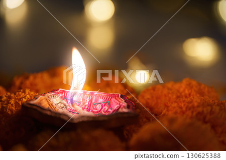 Diwali Celebration. A diya lamp shining brightly surrounded by marigold petals. 130625388