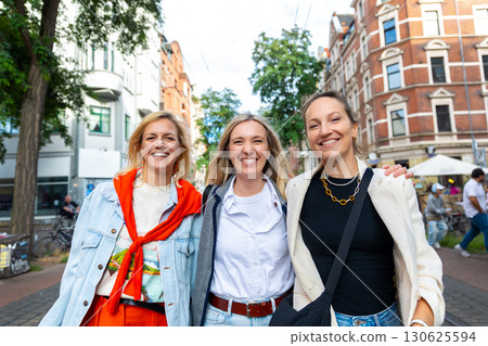 Three cheerful young adult women friend walk street old european german Hannover city street enjoy having fun laughing sunny day together. Female persons friendship celebration party weekend 130625594