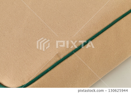 Close-up of beige fabric with green border showing detailed texture 130625944