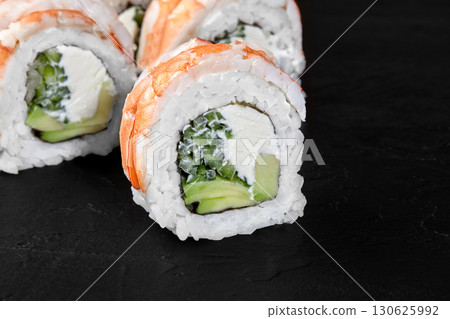 Sushi rolls with shrimp, avocado, cucumber, cream cheese and rice lying on dark background Sushi rolls with shrimp, avocado, cucumber, cream cheese and rice lying on dark background 130625992