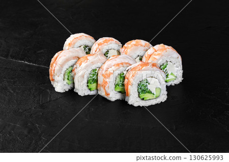 Sushi rolls covered with salmon and filled with cucumber, avocado and cream cheese resting on dark background Sushi rolls covered with salmon and filled with cucumber, avocado and cream cheese resting on dark background 130625993