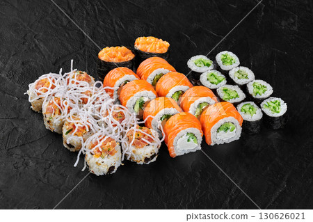 Sushi set displayed on black slate featuring salmon, cucumber, and various toppings Sushi set displayed on black slate featuring salmon, cucumber, and various toppings 130626021