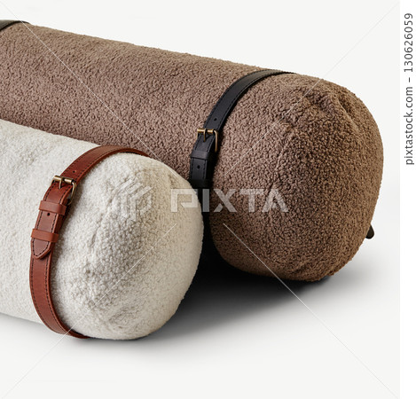 Two fluffy bolster cushions with leather straps resting on white surface 130626059