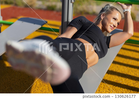 Woman exercising outdoors on equipment and monitoring activity with smart technology. 130626177