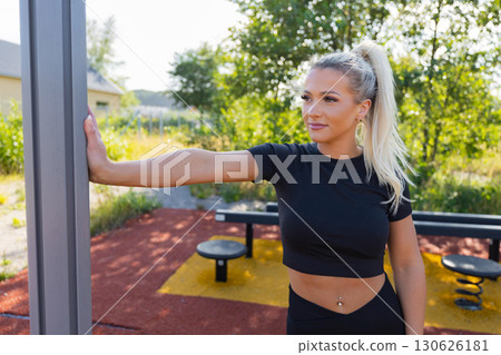 Woman stretching outdoors at a fitness park under sunny weather 130626181