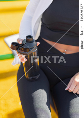 Female athlete with fitness wear holding a water bottle during outdoor exercise Female athlete with fitness wear holding a water bottle during outdoor exercise 130626187