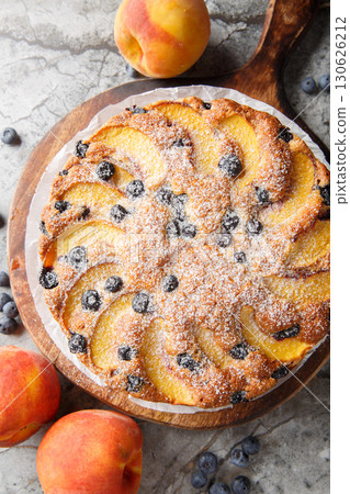 blueberry peach cake is soft, moist, and bursting with juicy fruit flavor closeup on the wooden board on the table. Vertical top view 130626212