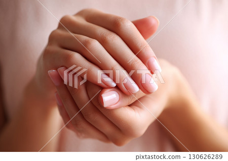 Classic French manicure highlights beautifully shaped nails, with a subtle pink hue and white tips. Hands rest gently together, showcasing a polished and elegant look in a serene setting Classic French manicure highlights beautifully shaped nails, with a subtle pink hue and white tips. Hands rest gently together, showcasing a polished and elegant look in a serene setting 130626289