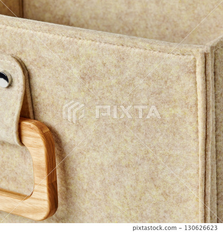 Beige felt storage box with wooden handle showing soft texture 130626623