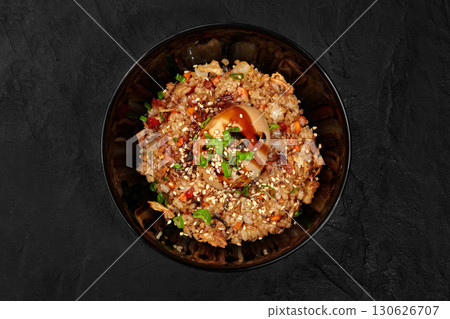 Delicious fried rice dish with egg and sesame seeds in black bowl Delicious fried rice dish with egg and sesame seeds in black bowl 130626707
