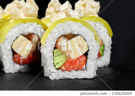 Uramaki sushi rolls with mango, salmon, tamagoyaki, shrimp, avocado, and cream cheese on dark background 130626804