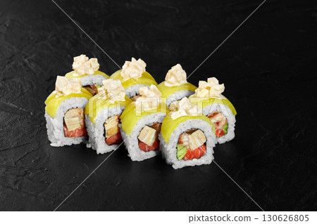 Uramaki sushi rolls with mango and crispy onions topping resting on dark background 130626805