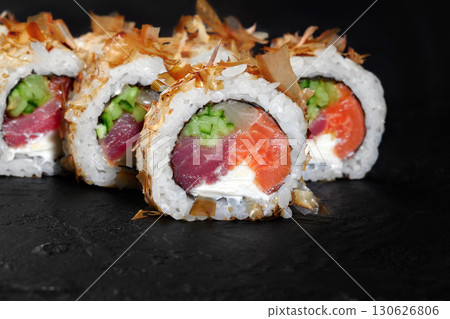 Delicious uramaki sushi rolls with tuna, salmon, cucumber and cream cheese on black background Delicious uramaki sushi rolls with tuna, salmon, cucumber and cream cheese on black background 130626806