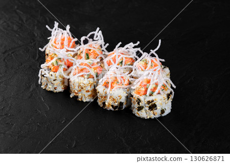 Salmon uramaki sushi rolls with cucumber and crispy topping on black background Salmon uramaki sushi rolls with cucumber and crispy topping on black background 130626871