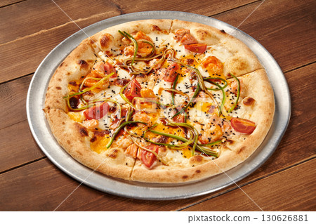 Delicious pizza with salmon, cucumber, tomato and sesame seeds resting on wooden table Delicious pizza with salmon, cucumber, tomato and sesame seeds resting on wooden table 130626881
