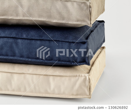 Stack of beige and blue square cushions forming a relaxing pile Stack of beige and blue square cushions forming a relaxing pile 130626892