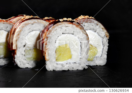 Delicious sushi rolls with eel, mango, cream cheese, and sesame seeds on dark background 130626934