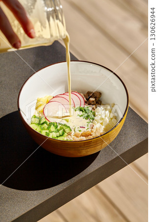 Chef pouring creamy sauce on okroshka, traditional russian cold soup 130626944