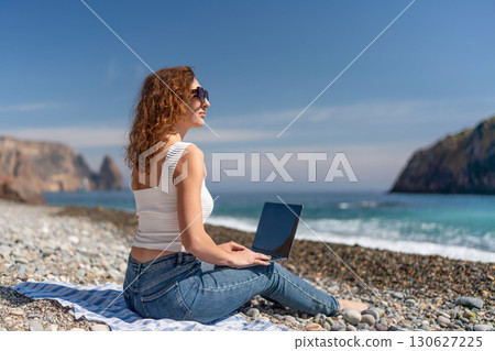Beach Laptop Woman: Working on the rocky beach during a sunny summer day for relaxation. Beach Laptop Woman: Working on the rocky beach during a sunny summer day for relaxation. 130627225