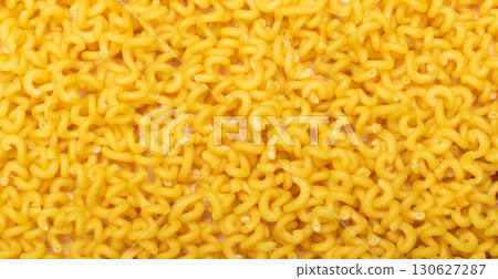 Raw yellow cavatappi pasta texture background top view. Pile of dry uncooked noodles pattern 130627287
