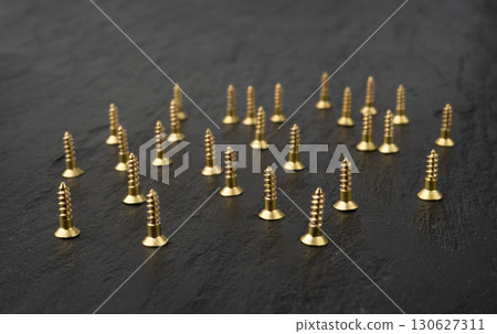 Yellow metal screws pile. Gold bolts close up 130627311