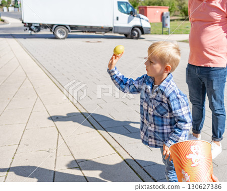 Child in plaid shirt participates in fair game. Symbol of childhood leisure, concentration, amusement and outdoor fun. 130627386