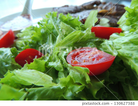 Roasted beef on a pillow of fresh salad leaves and cherry tomatoes closeup stock photo 130627388