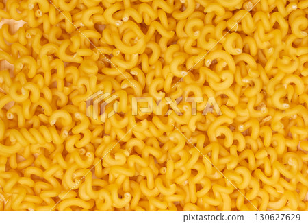Raw yellow cavatappi pasta texture background top view. Pile of dry uncooked noodles pattern 130627629