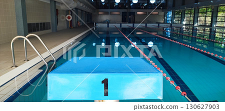 An empty indoor pool with dividing ropes and starting block number one. The concept of championship, victory, a place for swimming competitions and training. 130627903