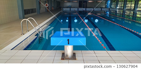 An empty indoor pool with dividing ropes and starting block number one. The concept of championship, victory, a place for swimming competitions and training. 130627904