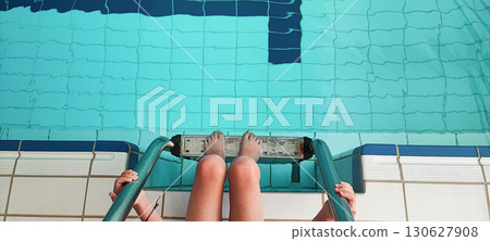 A smiling child climbs the stairs in an indoor swimming pool. Concept of swimming lessons for children, teaching water sports and healthy lifestyle A smiling child climbs the stairs in an indoor swimming pool. Concept of swimming lessons for children, teaching water sports and healthy lifestyle 130627908