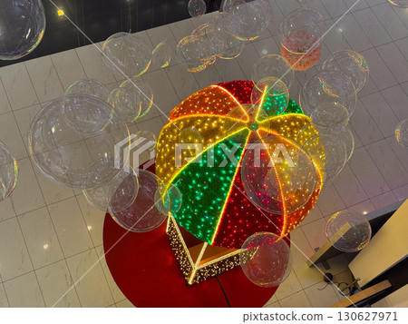 Colorful illuminated balloon sculpture displayed in shopping mall interior. Festive decoration, holiday entertainment and creative installation with light art and public attraction. Colorful illuminated balloon sculpture displayed in shopping mall interior. Festive decoration, holiday entertainment and creative installation with light art and public attraction. 130627971