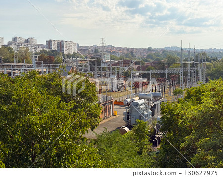 Electric substation with transformers and grid infrastructure near city. Industrial facility, energy distribution and urban development with power supply and engineering process. Electric substation with transformers and grid infrastructure near city. Industrial facility, energy distribution and urban development with power supply and engineering process. 130627975