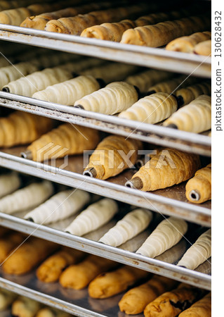 Assortment of croissants, eclairs, and pastry tubes on metal trays in bakery kitchen Assortment of croissants, eclairs, and pastry tubes on metal trays in bakery kitchen 130628432