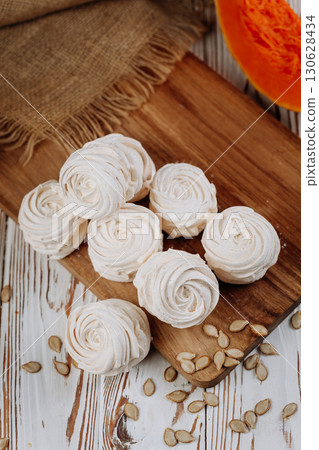 Homemade pumpkin marshmallows on rustic wooden table with seeds and autumn decor 130628434