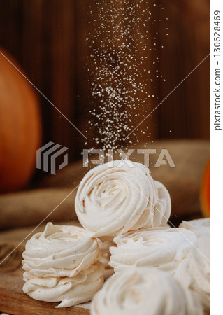 Pumpkin marshmallow sweets with powdered sugar falling, rustic autumn wooden background Pumpkin marshmallow sweets with powdered sugar falling, rustic autumn wooden background 130628469