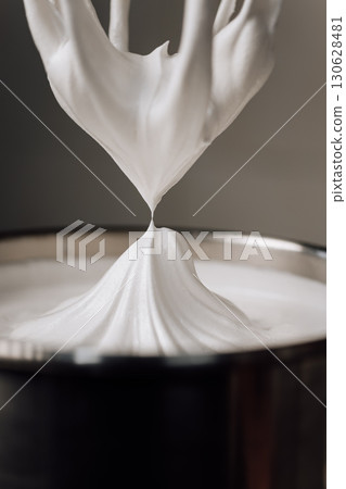 Freshly whipped marshmallow mixture on a whisk in a pastry kitchen, close-up 130628481