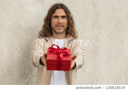 Happy handsome caucasian man giving red gift box with love. Birthday. Romantic surprise and celebration. Greeting card. 130628514