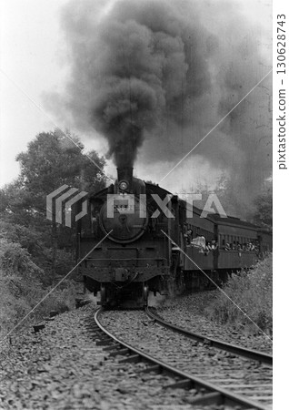 一輛蒸汽機車飛馳而過，濃煙滾滾。 130628743
