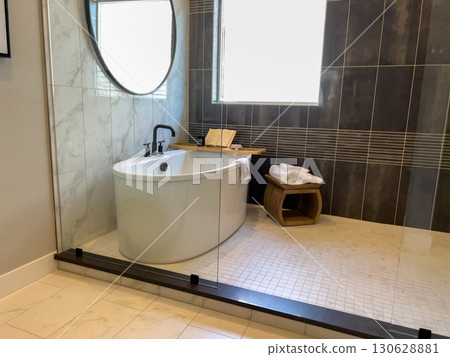 A stylish bathroom features a white freestanding tub, glass shower enclosure, black fixtures, and dark tile walls for a contemporary feel. A stylish bathroom features a white freestanding tub, glass shower enclosure, black fixtures, and dark tile walls for a contemporary feel. 130628881