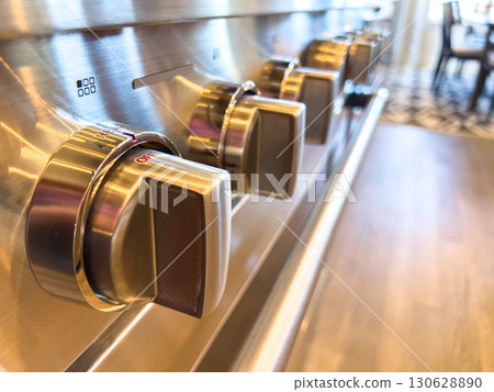 A close look at a modern gas range burner with a circular grate and brushed steel surface. The setup captures high-end design and utility in a residential kitchen. 130628890