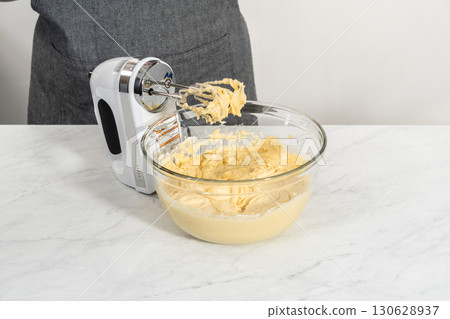 Mixing ingredients in a large glass mixing bowl to bake lemon blueberry bundt cake. 130628937